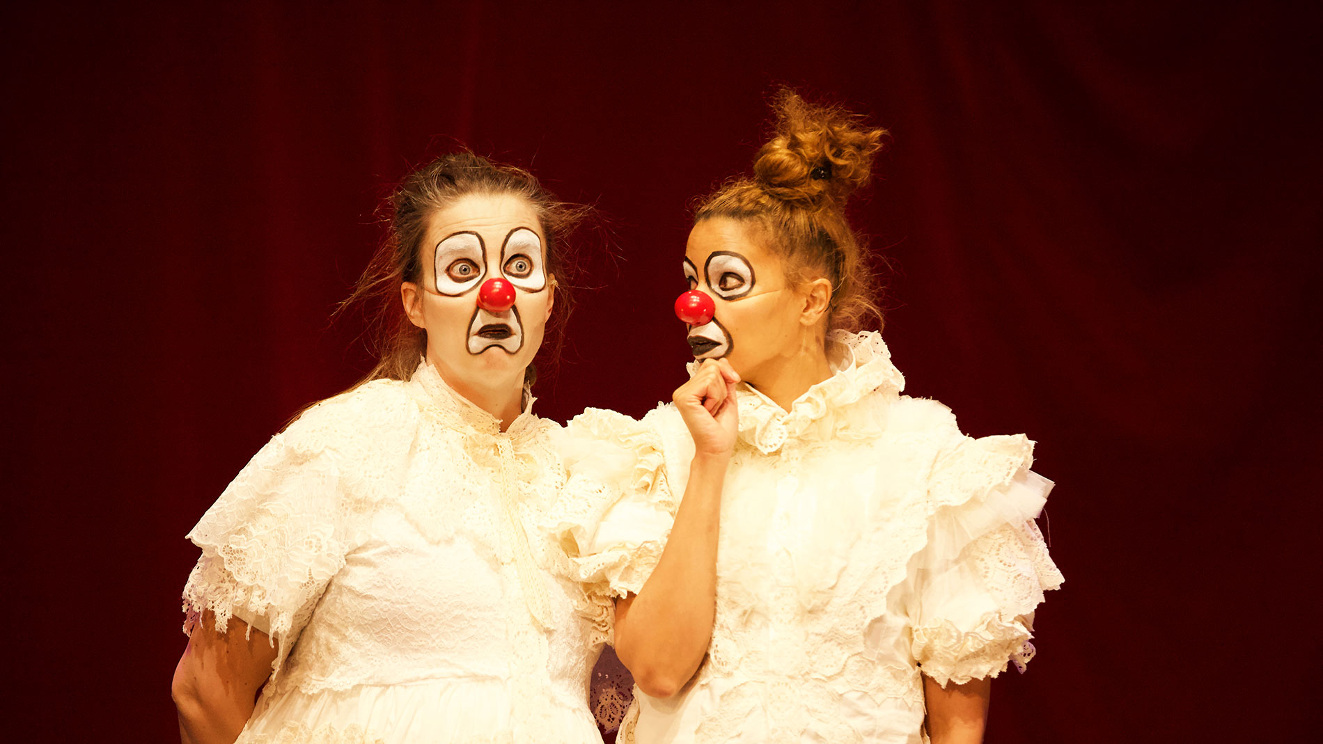 Two clowns wearing white dresses.